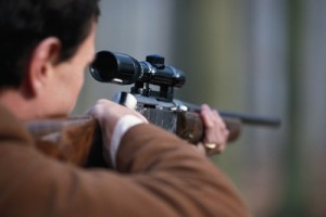 Man aiming rifle, close-up, rear view