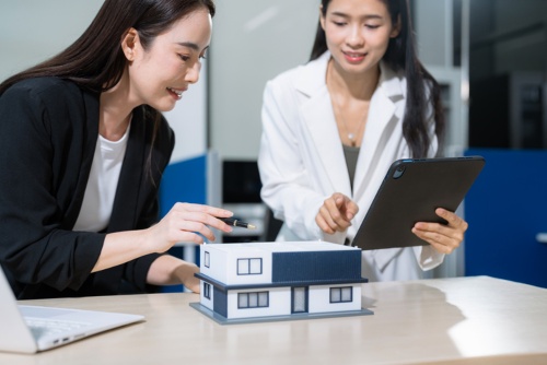 People reviewing a house model and property details before a real estate